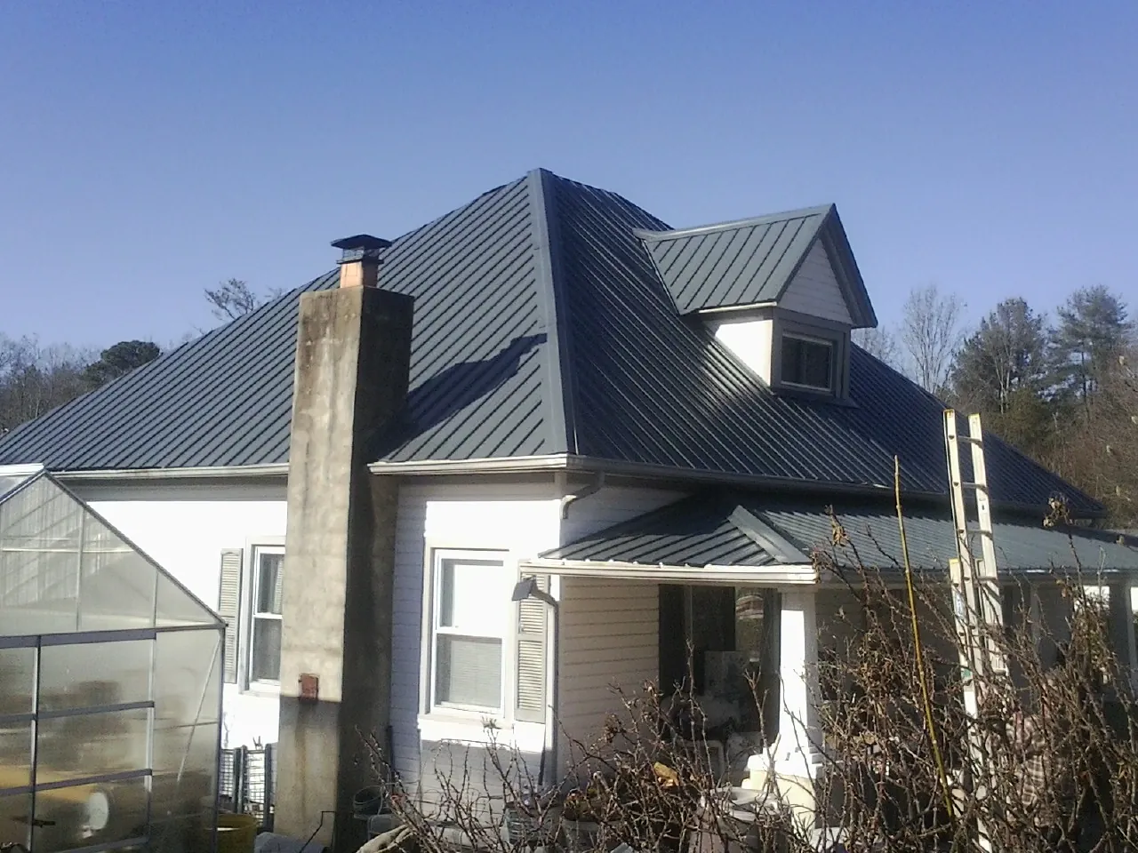 Dark blue standing seam metal roof on a white farmhouse with dormer — Slate & Tile Roof Repair by Roofing Brothers in Council