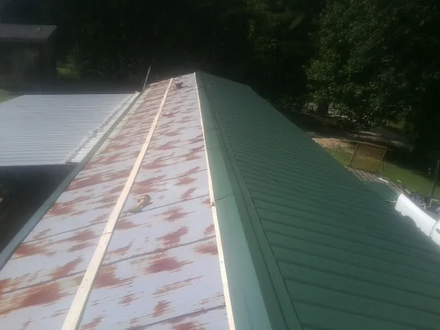 Old rusted panels beside newly installed green metal roofing — Wind Damage Roof Repair by Roofing Brothers in Council