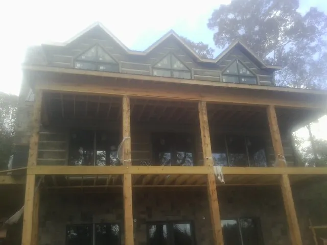 Dormers and porch framing on a large log home under construction — Roof Coating work by our crew in Council