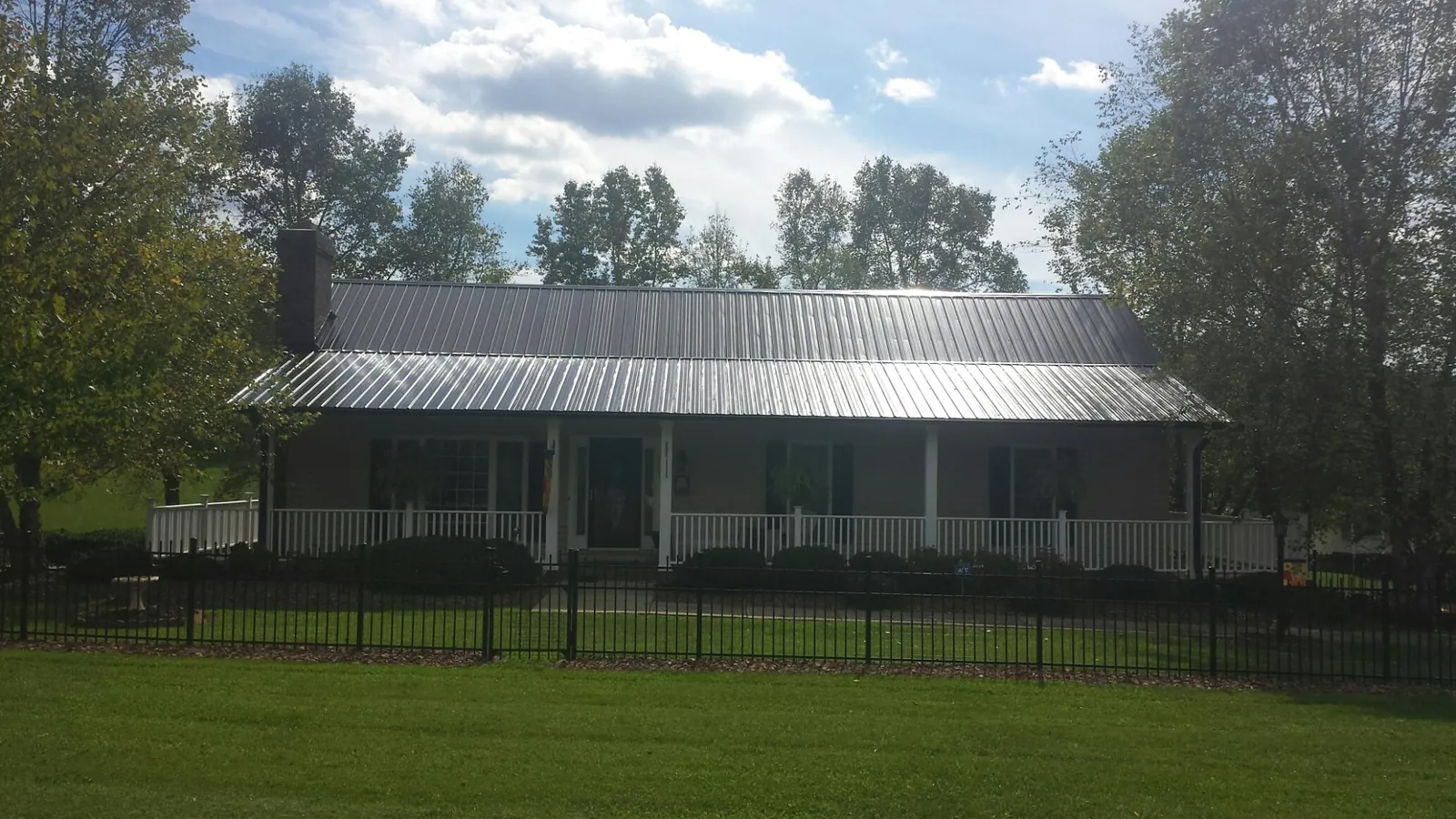 Gray metal roof on a brick ranch with a full width front porch — Gutter Guard Installation work by our crew in Council